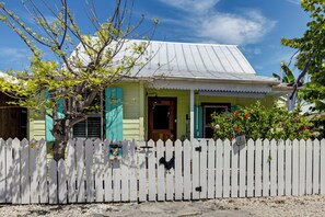 A house with a white picket fence, a metal roof, and a wooden door. - Walk to Southernmost Point! Conch Cottage w/ Patio (Key West)