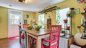 A dining area with a wooden table, red chairs, a red bench, and potted plants. - Walk to Southernmost Point! Conch Cottage w/ Patio (Key West)