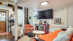 A cozy living room with a sofa, a television, and a wooden floor. - Walk to Southernmost Point! Conch Cottage w/ Patio (Key West)