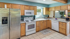 A kitchen with wooden cabinets, stainless steel appliances, a microwave, stove, and a dishwasher. - Lehigh Acres Home w/ Large Yard & Private Patio (Lehigh Acres)