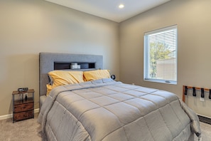 A bedroom with a bed, bedside table, and a window with blinds.
