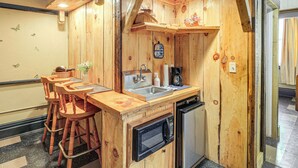 Een houten keuken met een spoelbak, fornuis en barstoelen.