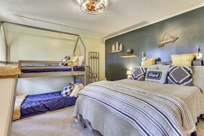 A bunk bed with a lower bunk, a single bed with striped bedding, a wall-mounted shelf with decorative items, and a ceiling light fixture. - Laurelville Home w/ Hot Tub & Fire Pit (Laurelville)