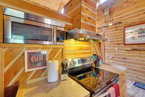 A kitchen with a stainless steel stove, oven, and microwave, wooden walls, and a ceiling with wooden beams. - 3-Cabin Base w/ Lake Access: Dogs Welcome! (Soldotna)