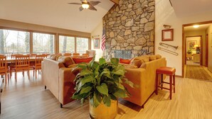 A spacious living room with a stone wall, a large plant, a sofa, and a dining area with wooden furniture. - 2 Private Pools! Stunning Southaven Group Getaway (Southaven)