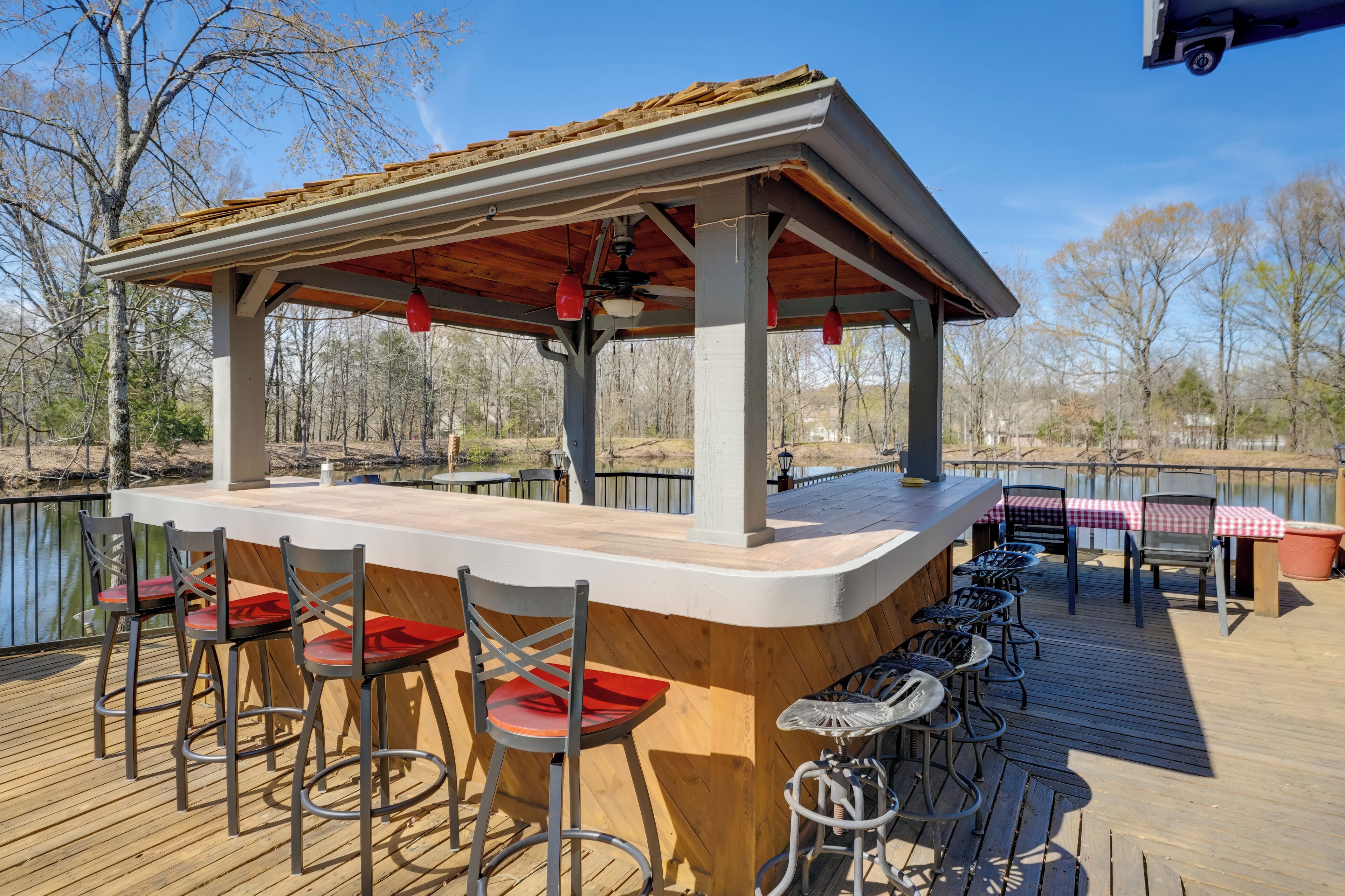 Une terrasse en bois avec un espace bar, des tabourets de bar et un coin salon abrité.