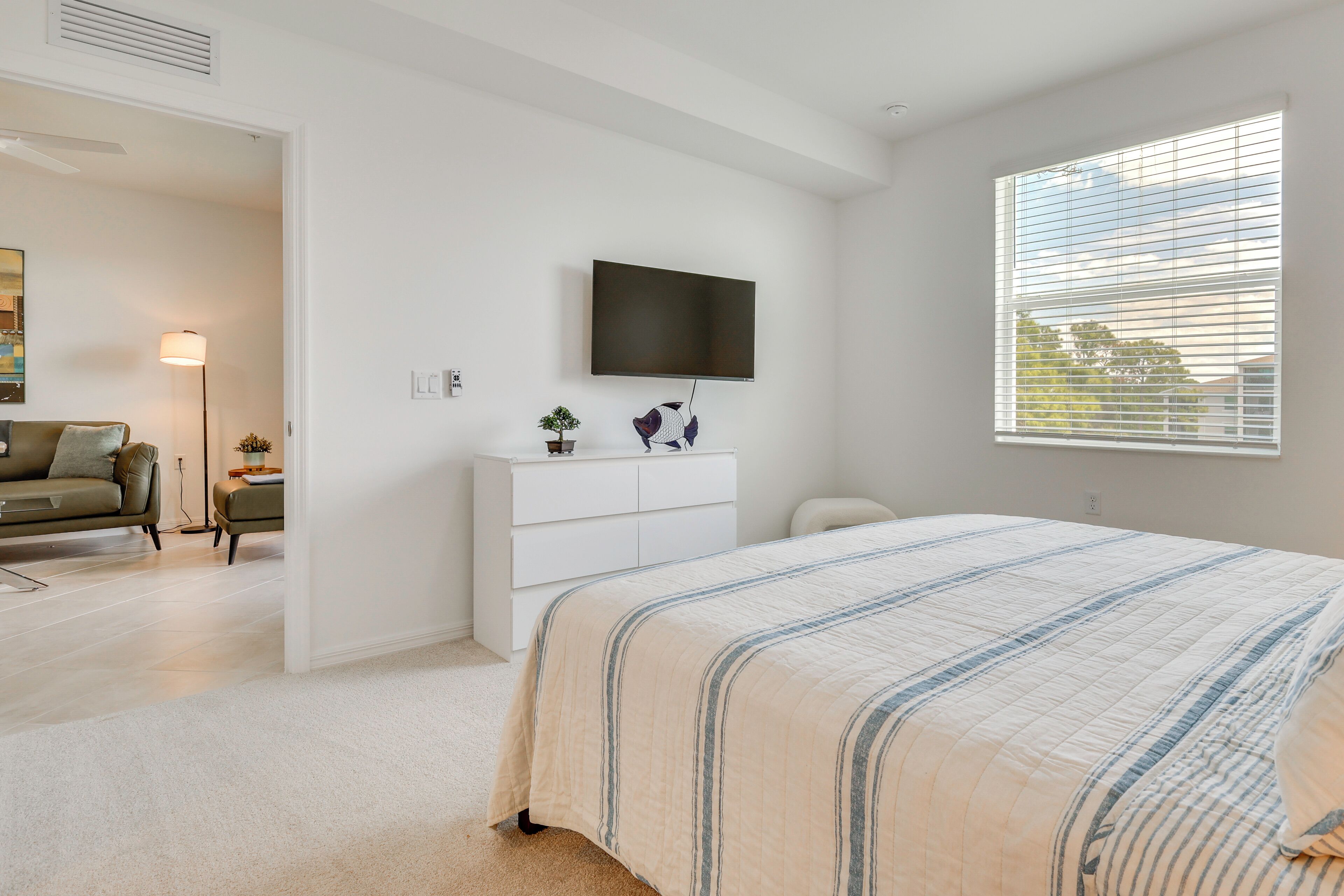 A bedroom with a bed, a TV, a dresser, and a window.