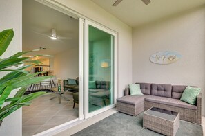 A living area with a sliding glass door, a sofa, a coffee table, and a potted plant. - Golf + Poolside Fun! Extended Base in Ibis Landing (Lehigh Acres)