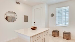 Een moderne badkamer met een witte wastafel, een ronde spiegel, een houten schaal op het aanrecht en rieten manden.