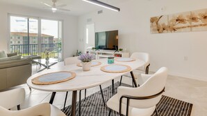 Een moderne eetruimte met een ronde tafel, witte stoelen en een plafondventilator.