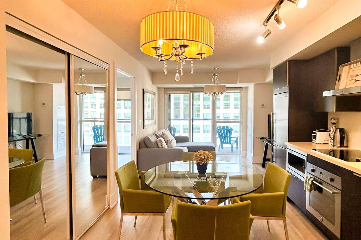 A modern kitchen with a dining area, a sofa, and a large window.