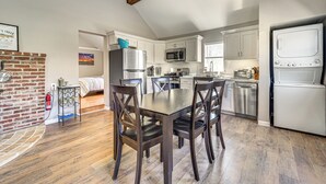 Una cucina moderna con mobili bianchi, elettrodomestici in acciaio inossidabile e un'area pranzo con sedie in legno scuro.