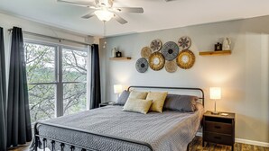 Een slaapkamer met een bed, nachtkastjes, een plafondventilator en decoratie aan de muur.