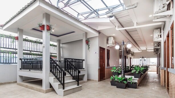 A covered outdoor area with a staircase, potted plants, and a corridor with a tiled floor. - Cozy Double Escape W/ Free WiFi and Parking (Medan)