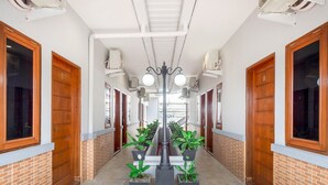 A corridor with wooden doors, air conditioning units, and potted plants. - Cozy Double Escape W/ Free WiFi and Parking (Medan)