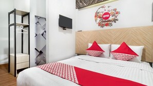 A hotel room with a bed, a TV mounted on the wall, a wardrobe, and a decorative wall piece. - Cozy Double Escape W/ Free WiFi and Parking (Medan)