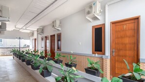 A hallway with multiple doors, air conditioning units, and potted plants. - Cozy Double Escape W/ Free WiFi and Parking (Medan)