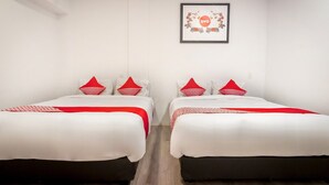 Habitación de hotel con dos camas, cada una con ropa de cama roja y blanca, un cuadro en la pared y suelo de madera.