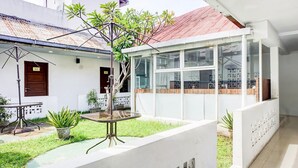 A modern building with a glass enclosure, a small garden area with a table and chairs, and a visible door labeled '112'. - Luxury Deluxe DBL Retreat W/ Free WiFi and Parking (Medan)
