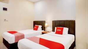 A hotel room with two beds, each with a red and white bedspread, a nightstand with a lamp, and a wall-mounted air conditioner. - Luxury Deluxe DBL Retreat W/ Free WiFi and Parking (Medan)