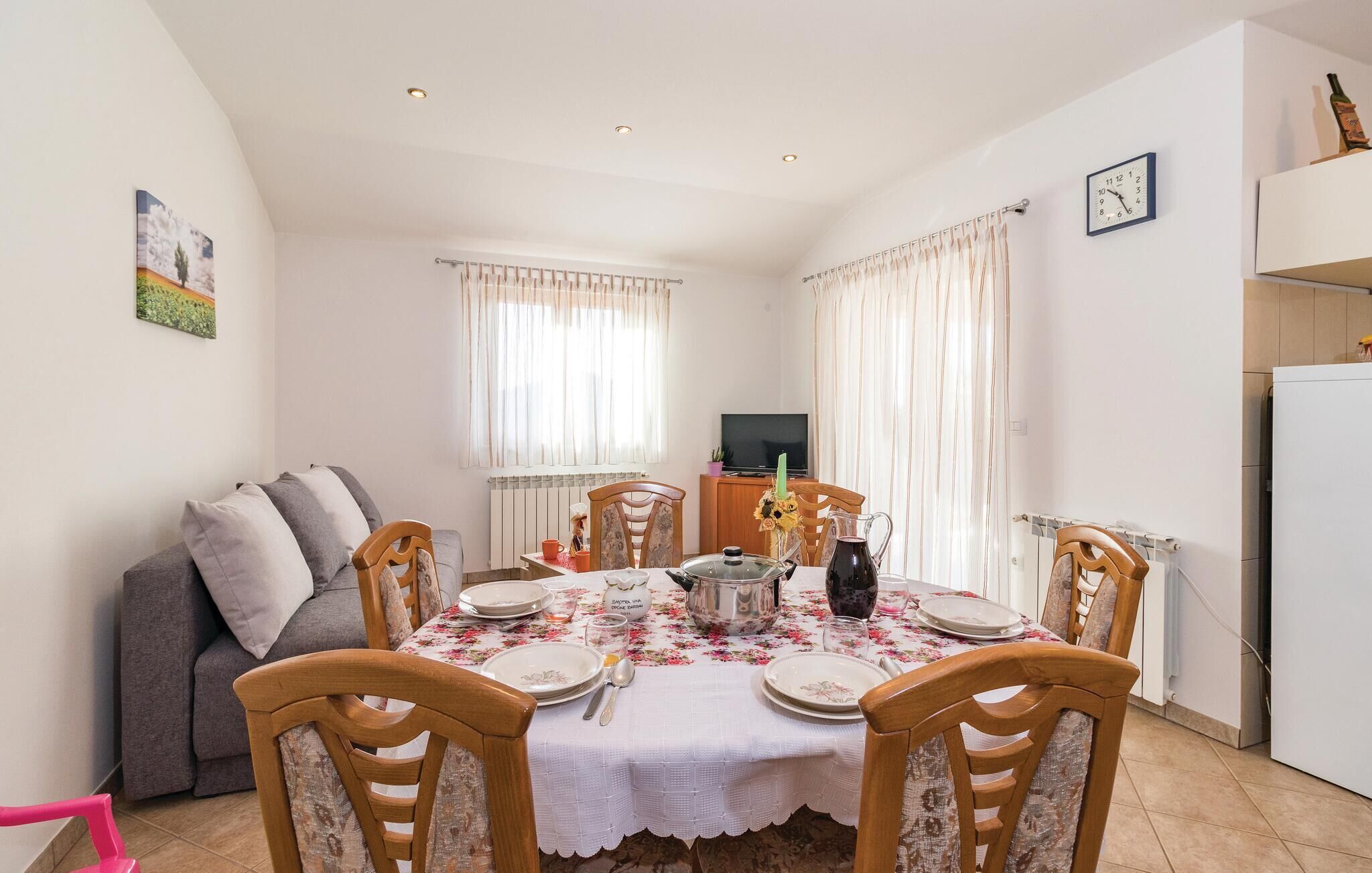 Un coin repas avec une table dressée pour quatre personnes, un canapé, un téléviseur et un réfrigérateur.