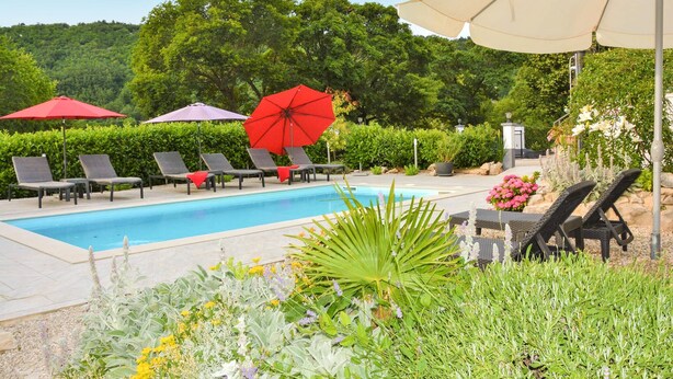 Zona de piscina amb gandules, ombrel·les i diferents plantes.