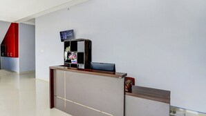 Un comptoir d’accueil doté d’un téléviseur à écran plat, d’un vase rempli de fleurs et d’un comptoir en bois.