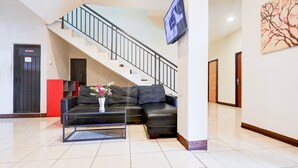 Ein Wohnzimmer mit Sofa, Couchtisch, Fernseher, Treppe und Tür.