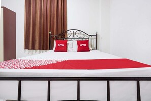 A bed with a white and red bedspread, two pillows with 'OYO' text, a brown curtain, and a black metal headboard. - Luxury Deluxe DBL Retreat W/ Free WiFi and Parking (Makassar)