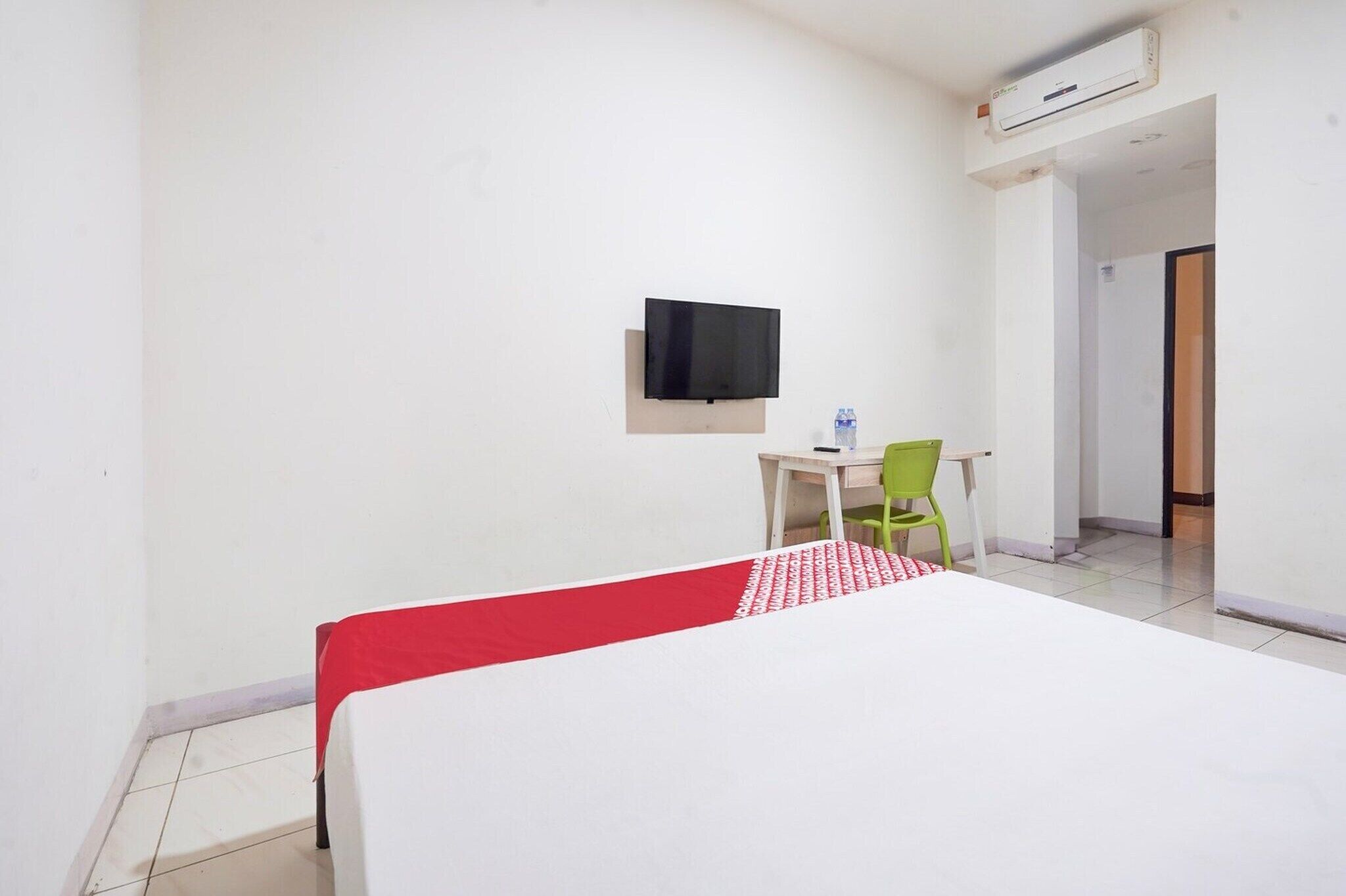 Hotellihuone, jossa on sänky, työpöytä, tuoli, televisio ja ilmastointilaite.