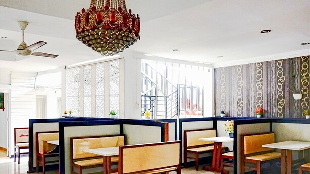 Un restaurante con cabinas, una araña y una escalera al fondo.