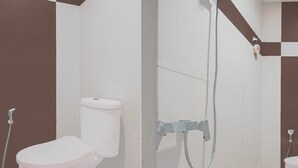 A bathroom with two toilets, a shower, and a towel rack.