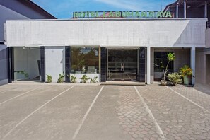 Hotellin sisäänkäynti, jossa on kyltti, jossa lukee ”HOTEL LABUHAN RAYA”, suuret lasiovet ja ruukuissa olevia kasveja.