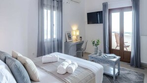 Ein Hotelzimmer mit Bett, Schreibtisch mit Lampe, Fernseher und Blick ins Freie.