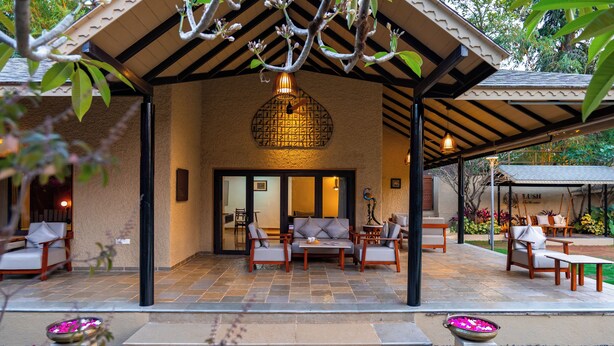 An outdoor patio area with a covered seating arrangement, a decorative light fixture, and a view of the interior through a glass door.