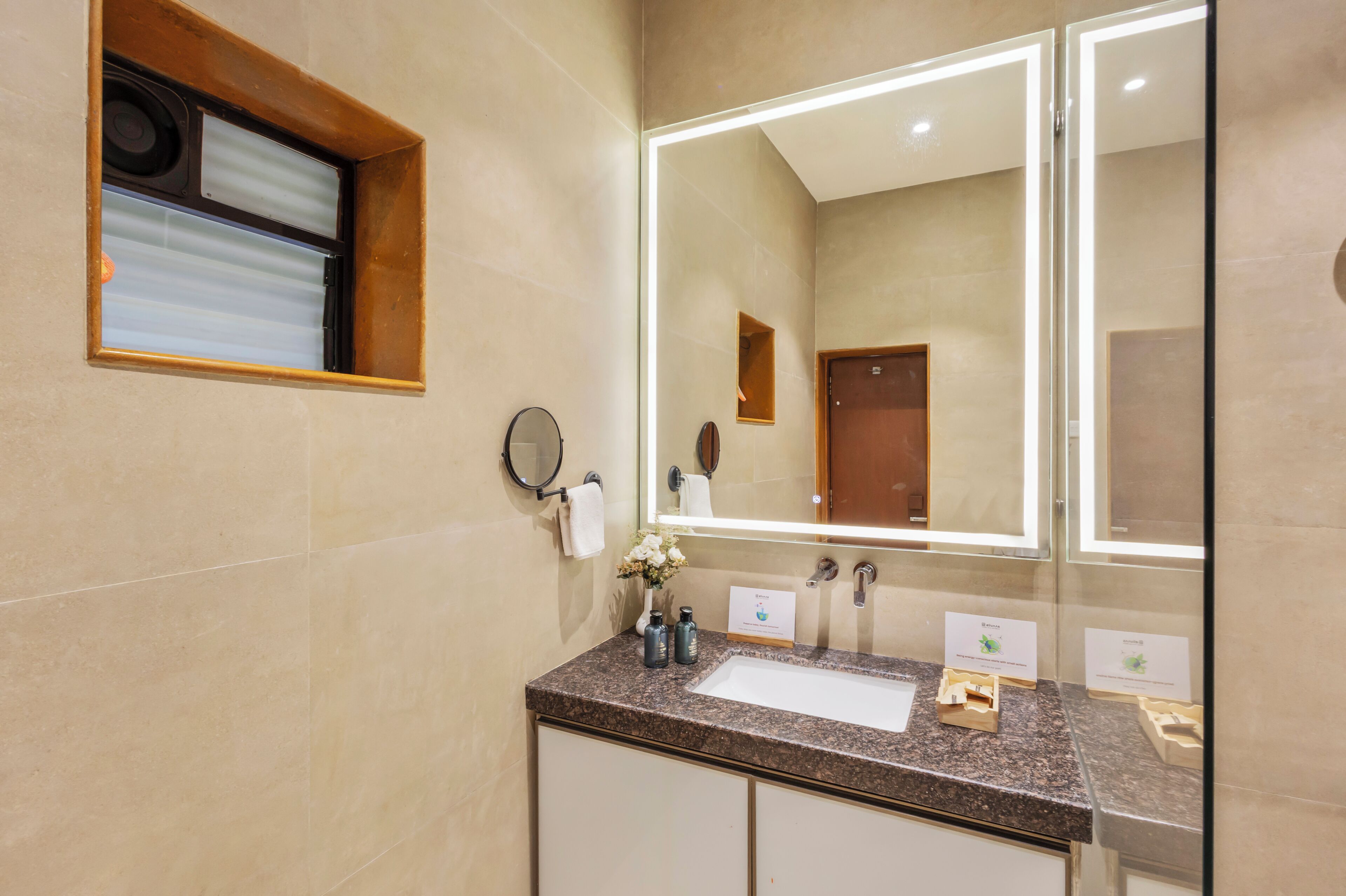A bathroom with a large mirror, a sink, and a towel rack.