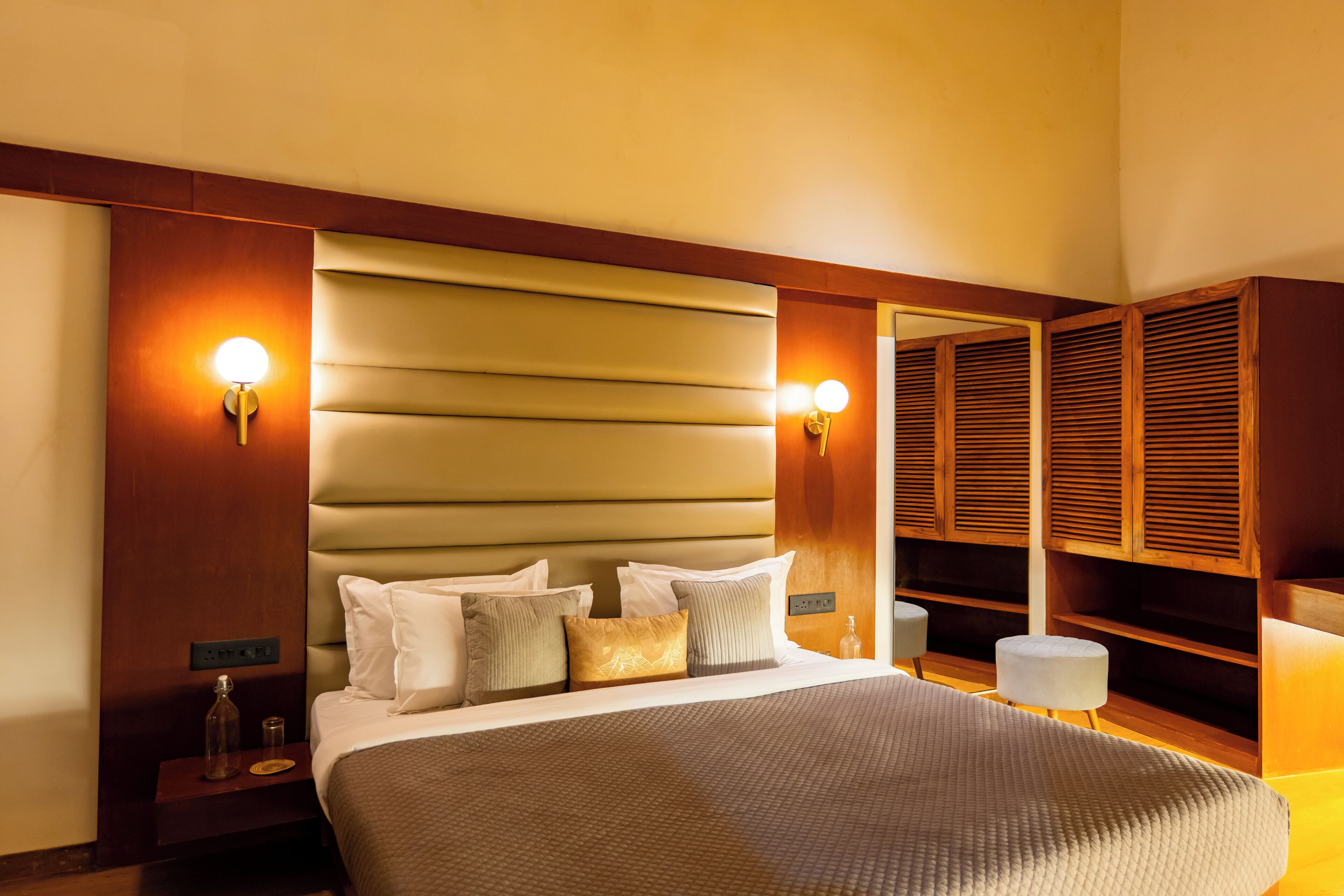Quarto de hotel com uma cama grande, luminárias de cabeceira, mesa de cabeceira e um espelho.