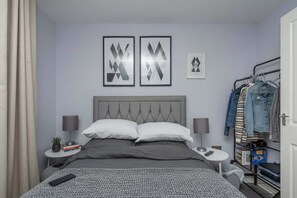 A neatly arranged hotel room with a bed, bedside tables, a wardrobe, and wall art. - London Flat with Private Entrance (London)
