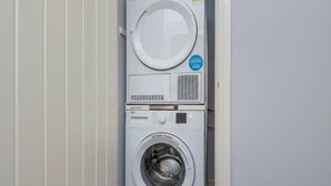 Un appareil combiné lave-linge et sèche-linge, de type « empilable », doté d’un panneau de commande et d’une porte circulaire.