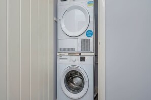 A stacked washer and dryer unit with a control panel and a circular door. - London Flat with Private Entrance (London)