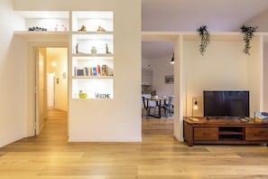 Ein Wohnzimmer mit einer Holztrennwand, einem Fernseher und einem Bücherregal mit verschiedenen Gegenständen.