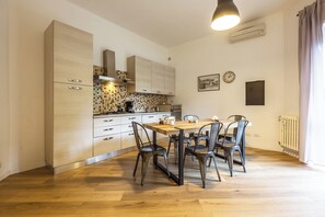 A modern kitchen with wooden cabinets, a tiled backsplash, and a dining area with a table and chairs. - Cozy Gianicolo apartment 2 steps from San Pietro (Roma)