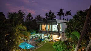 Una casa moderna con piscina, rodeada de vegetación exuberante y palmeras.
