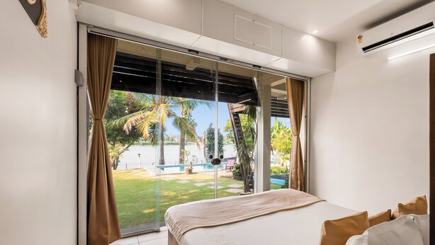 Un dormitorio con cama, cortinas, ventana y aire acondicionado.