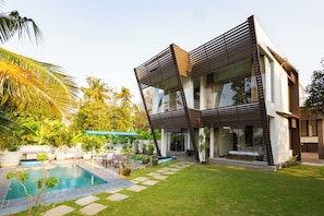 Une maison moderne dotée d’une piscine, d’un patio et d’un jardin.