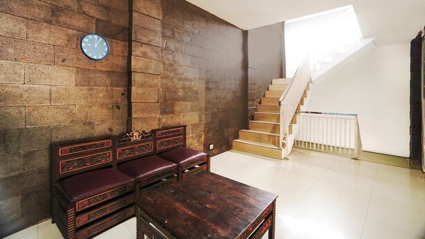 Une pièce avec un banc en bois, une table en bois, une horloge au mur et un escalier.