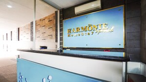 Un comptoir d’accueil avec une pancarte indiquant : « HARMONIE, hébergement chez l’habitant, expérience authentique ».