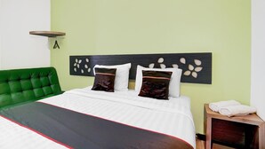 A neatly made bed with a green headboard, white bedding, and two decorative pillows.