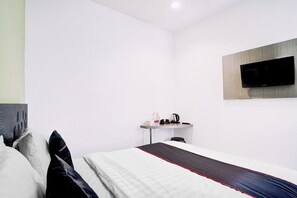 Ein Hotelzimmer mit Bett, einem Flachbildfernseher an der Wand, einem kleinen Tisch mit Wasserkocher und einem Sessel.