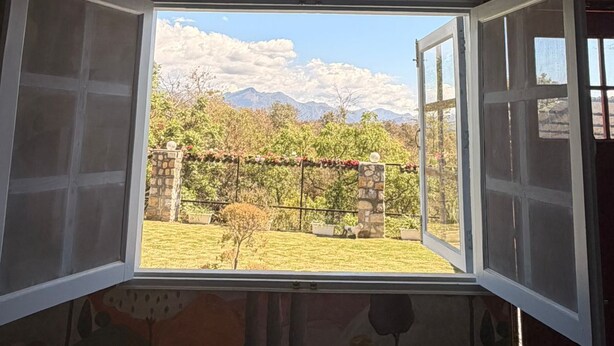 A room with an open window revealing a garden view. - The Amar Vilas (Dehradun)